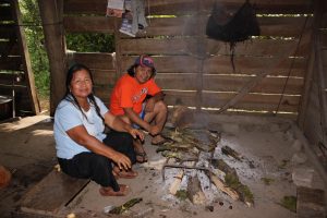 Fredy Grefa with his mom, Carmela Andi, grilling fish wrapped with bijao leaves.