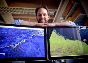Tamlin Pavelsky with Landsat images of the Alaska coast and the Tanana River in his office in Mitchell Hall at the University of North Carolina.