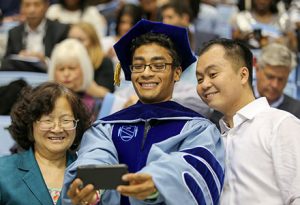 A graduate takes a photo with family prior to the 2015 Winter Commencement at the Dean E. Smith Center.