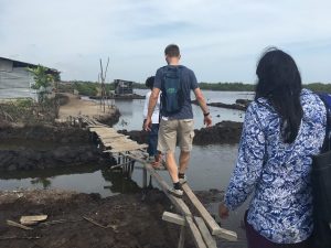 Jeff Austin and other members of the team from UNC and the CDC walk across a makeshift bridge in a neighborhood outside Monrovia.