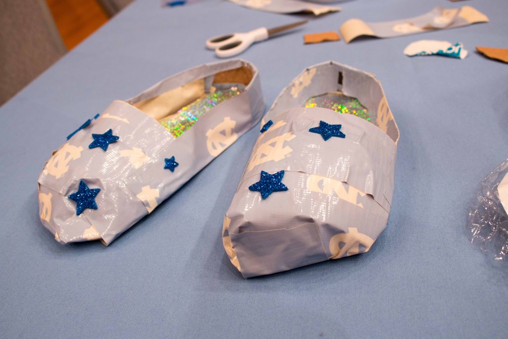A pair of shoes made from Carolina blue Duck Tape and cardboard and decorated with stars.