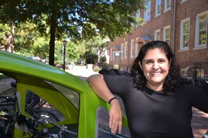 Carmen Huerta-Bapat stands next to “the elf,” the solar-powered motorized bike her husband, Navin Bapat, bought for her as a graduation present this spring. “He knew how much I wanted a bike that could accommodate our three daughters in the back seat,” she said.